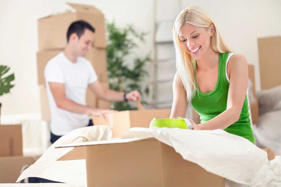 A woman in green shirt moving boxes with man.