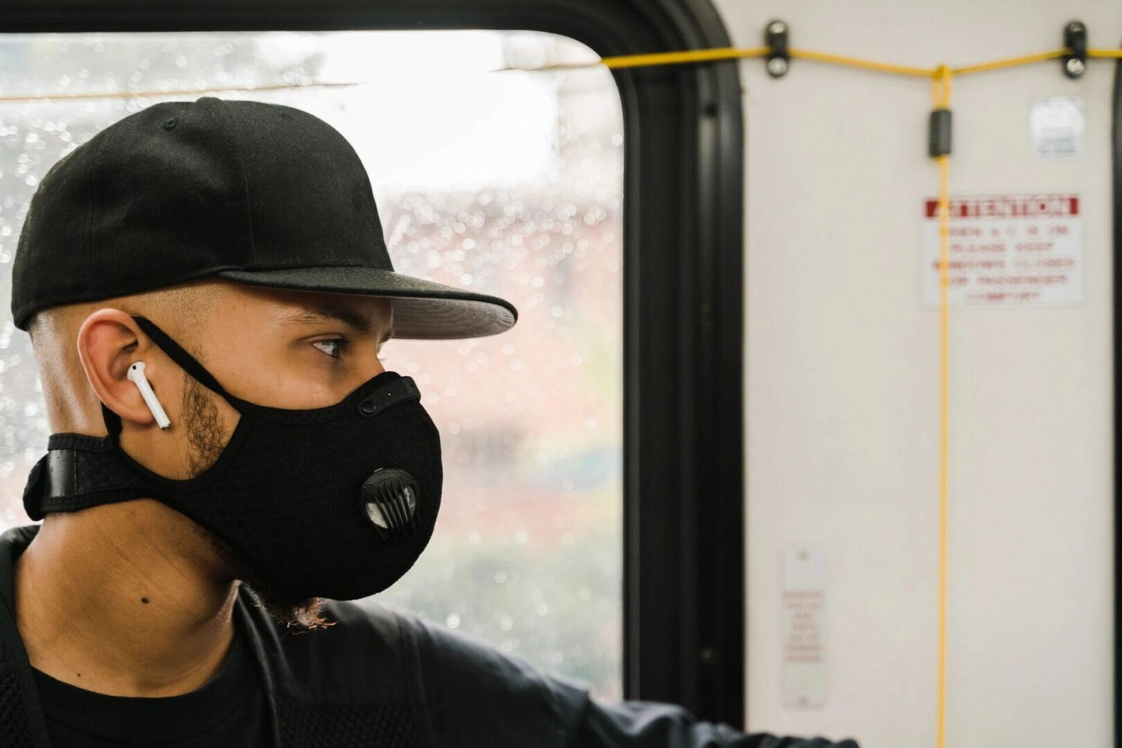 A man wearing a hat and mask on the bus.