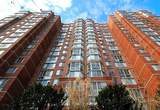 A tall brick building with many windows and trees.