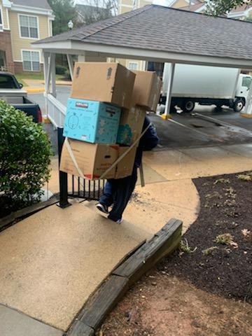 A person walking down the sidewalk with boxes on their back.