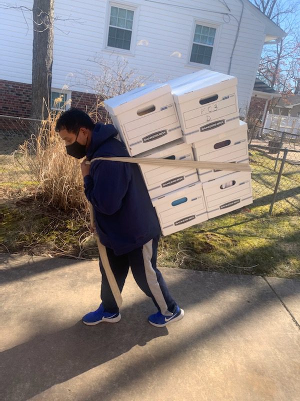 A man carrying boxes on his back while walking down the street.