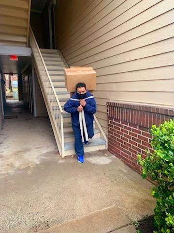 A man carrying boxes up the stairs of his house.