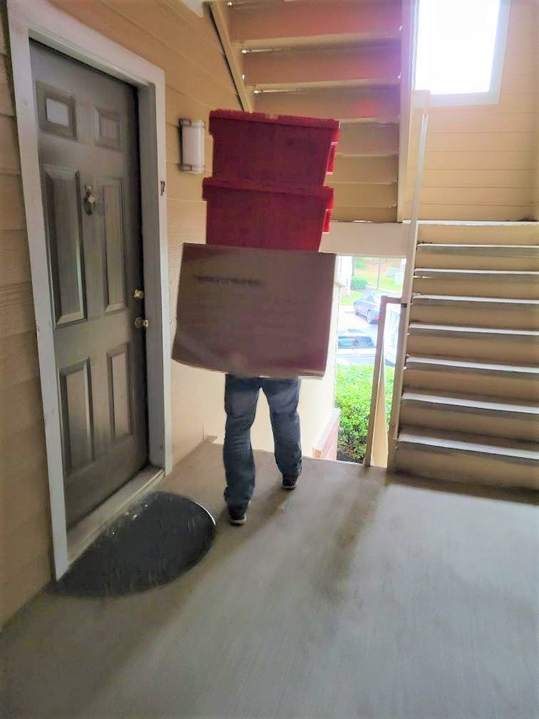 A person carrying boxes in front of the door.