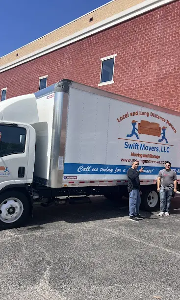 A couple of men standing next to a truck.