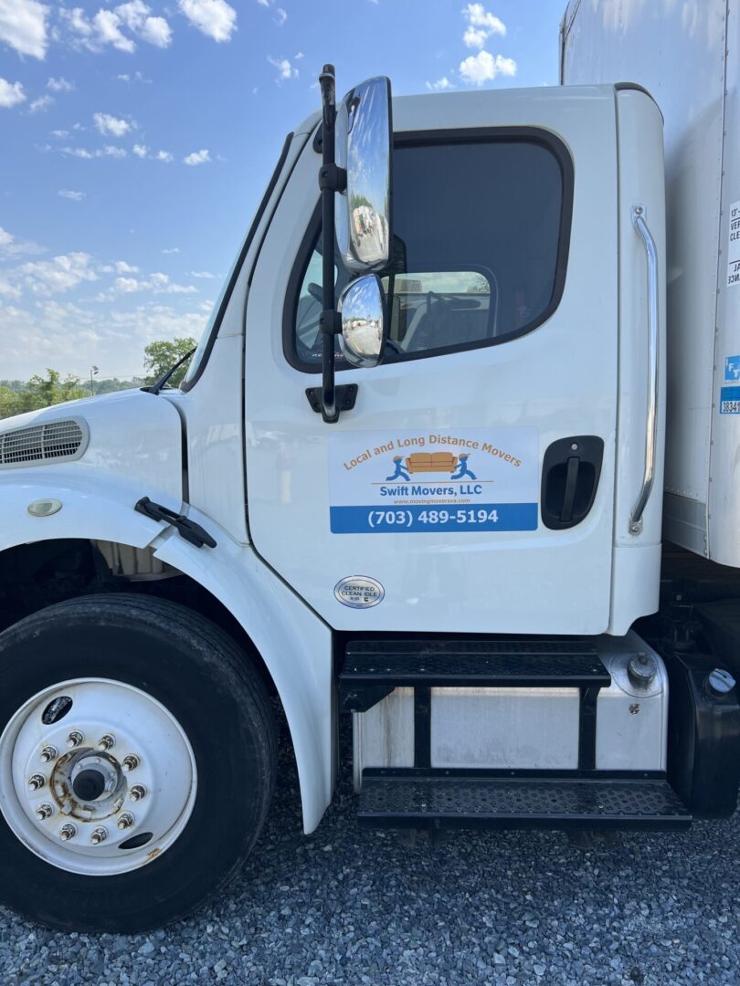 A white truck with blue lettering parked on the side of road.