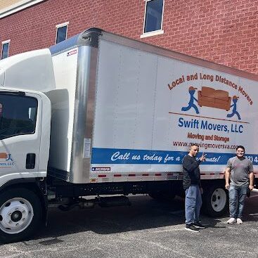 A couple of men standing next to a truck.